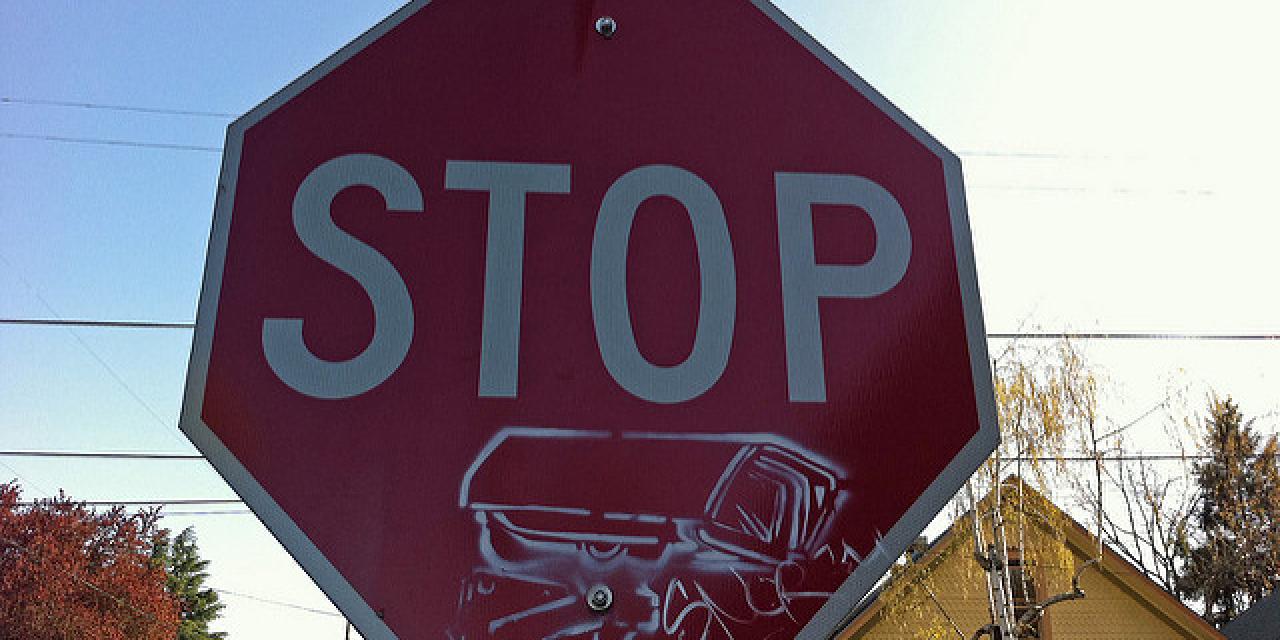 Ein Stop-Schild mit einem Stencil einer Überwachungskamera.