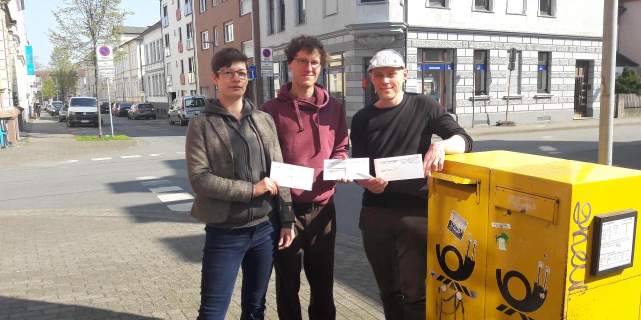 Drei Digitalcourage-Teammitglieder, die mit Briefen in der Hand vor einem Briefkasten stehen.