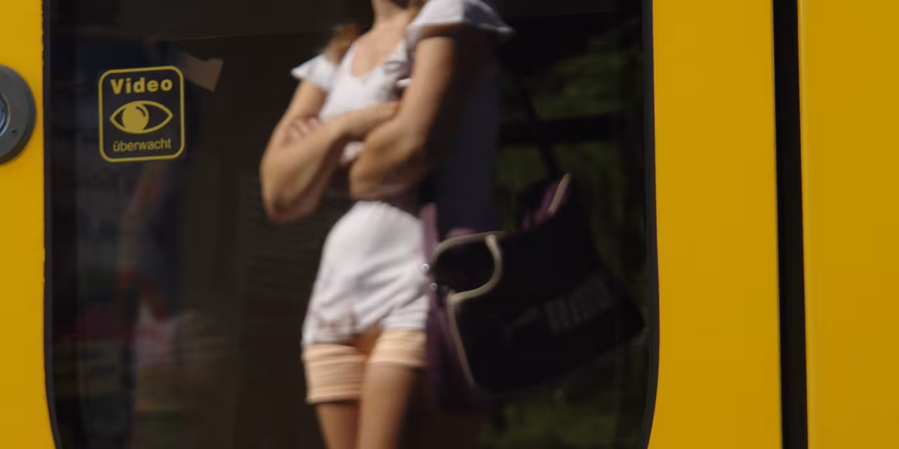 Eine wartende Person spiegelt sich in der Scheibe einer Straßenbahn.