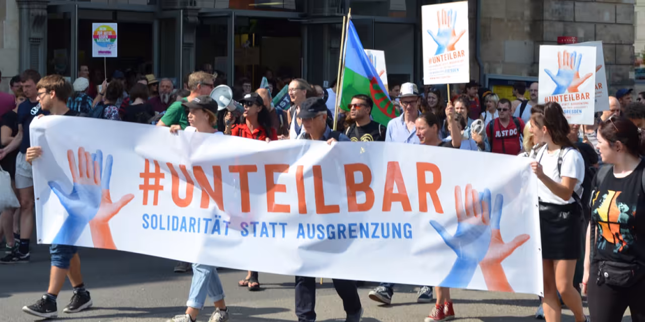 Demonstrant.innen mit einem riesigen „#unteilbar“-Banner.