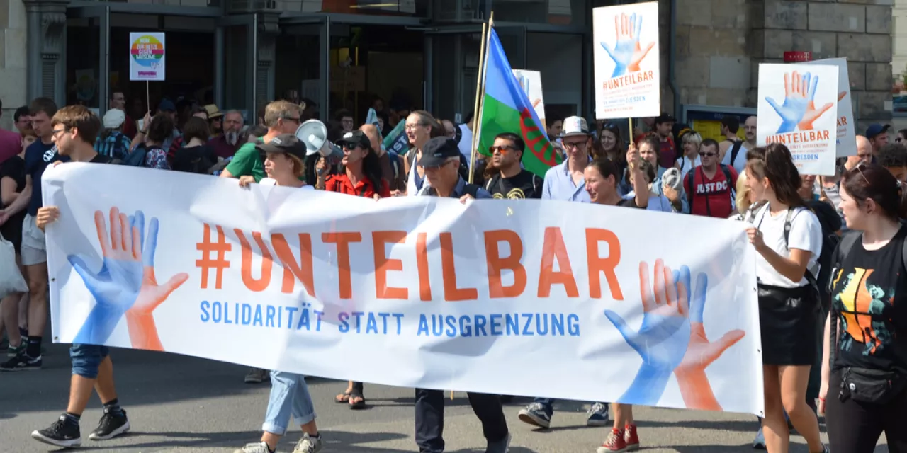 Demonstrant.innen mit einem riesigen „#unteilbar“-Banner.