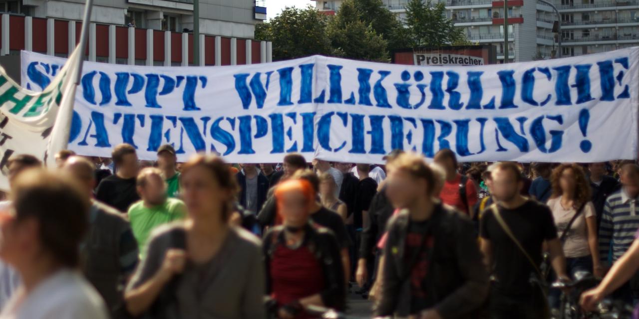 Demonstrant.innen mit einem riesigen Banner „Stoppt willkürliche Datenspeicherung“.
