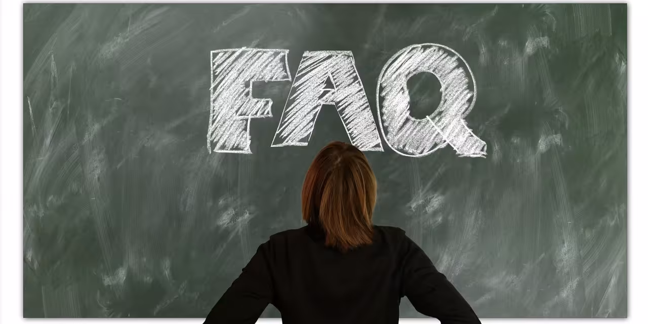 Eine Person, die vor einer Tafel steht, auf der FAQ steht.
