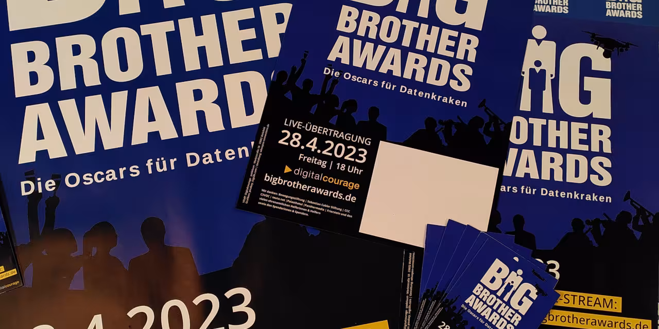 Verschiedene Werbeflyer und -plakate für die BigBrotherAwards 2023 auf einem Haufen drapiert.