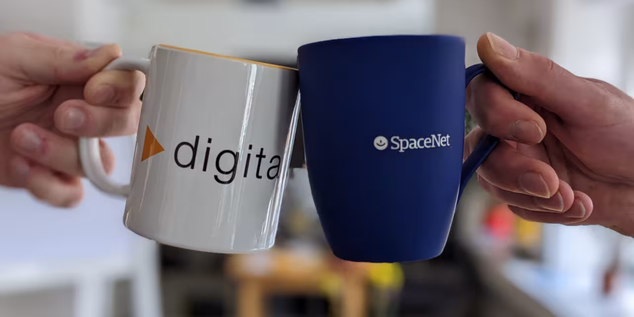 Die Hände von zwei Personen sind zu sehen, die mit Kaffeebechern anstoßen. Auf dem rechten, blauen Becher ist das Logo der SpaceNet AG zu sehen, auf dem linken, weißen Becher das Logo von Digitalcourage.