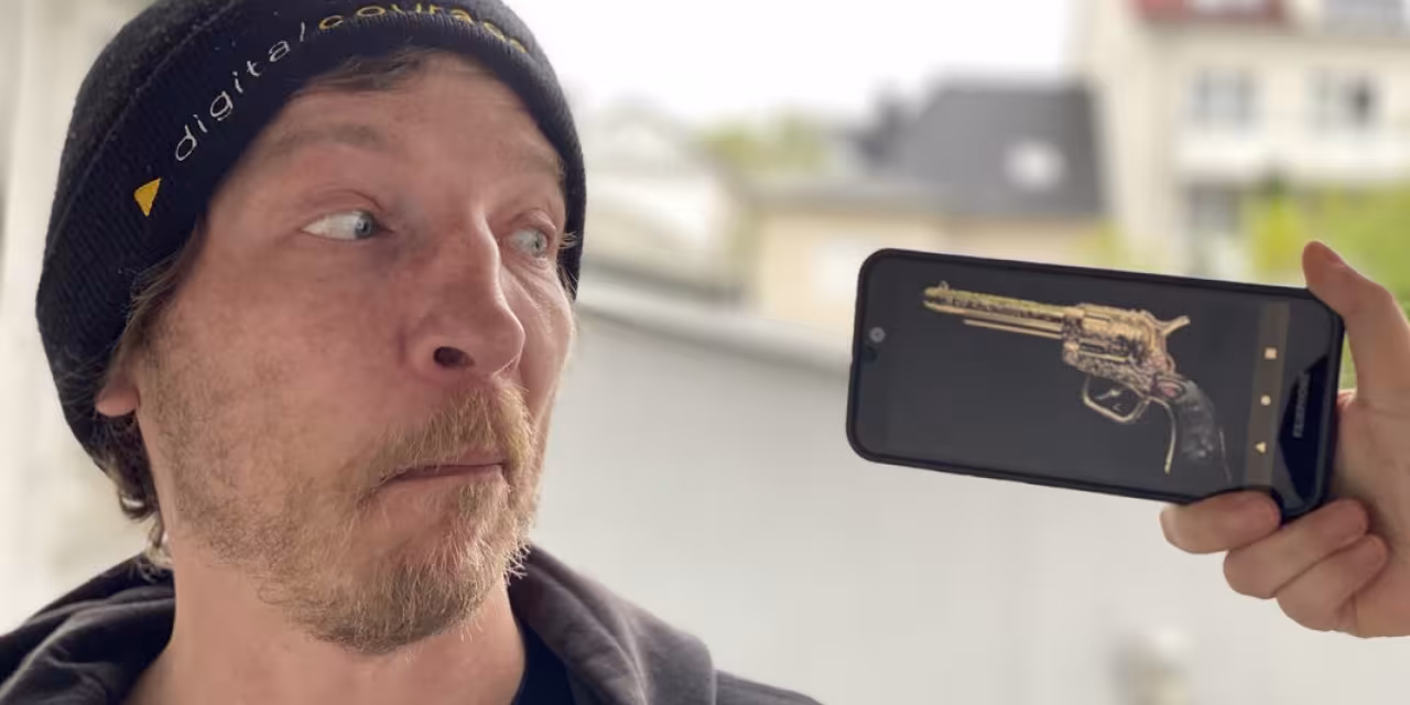 Mann wird von Revolverfoto bedroht, das auf einem Smartphone angezeigt wird.