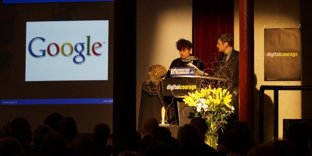 Rena Tangens und padeluun am Pult während der BBA-Verleihung 2013. Im Hintergrund ist das Google-Logo auf eine Wand projeziert.