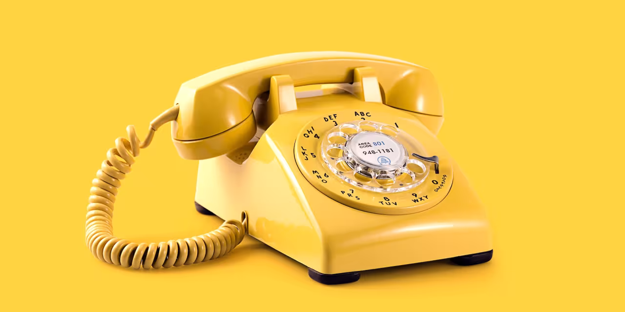Ein gelbes Wählscheibentelefon vor gelbem Hintergrund.