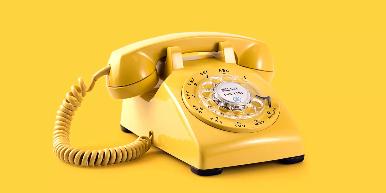 Ein gelbes Wählscheibentelefon vor gelbem Hintergrund.