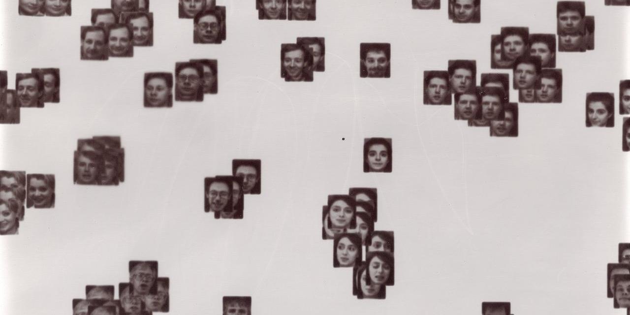 Ein Laptopogramm auf neutralem Hintergrund mit verstreuten, quadratischen Porträts, die alle einfarbig sind und nach Ähnlichkeit gruppiert wurden. Die Gruppen variieren in ihrer Größe und reichen von einzelnen Gesichtern bis hin zu sich überschneidenden Ansammlungen von bis zu zwölf Personen. Die Gesichtsausdrücke aller abgebildeten Personen sind neutral, vertreten durch eine Mischung aus Alter und Geschlecht.