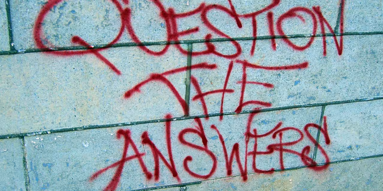 Beschmierte Wand mit dem Satz "Question the answers".