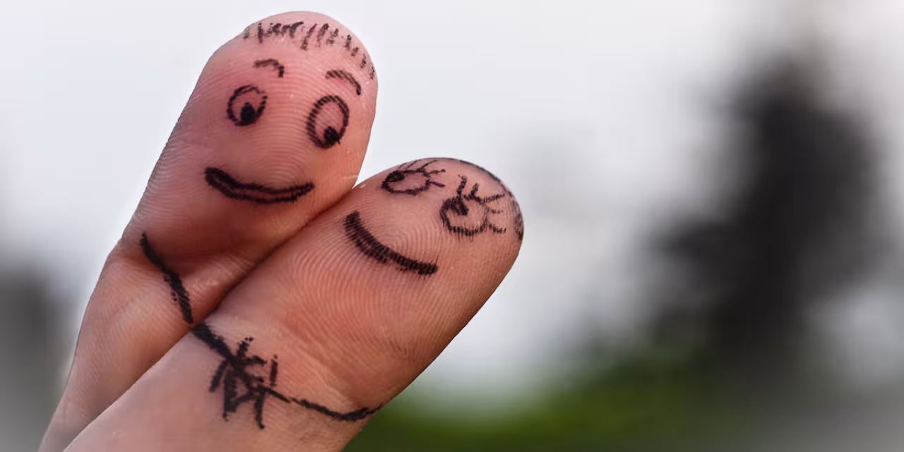 Zwei Finger haben verliebte Gesichter aufgemalt und flirten angeschmiegt miteinander.