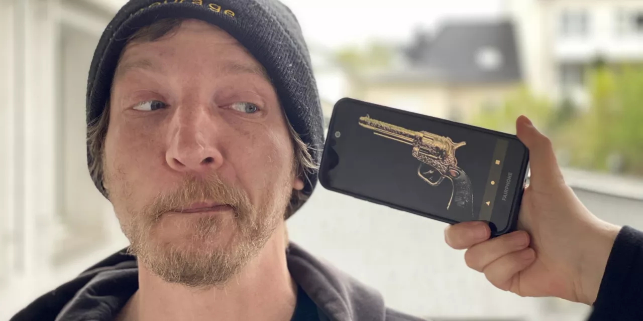 Eine Person, die verzweifelt auf ein Smartphone schaut, auf dem eine Revolver abgebildet ist.