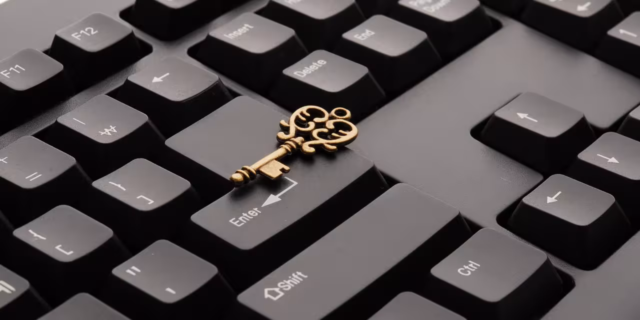 Ausschnitt einer schwarzen Tastatur. Darauf liegend ein goldener Schlüssel.