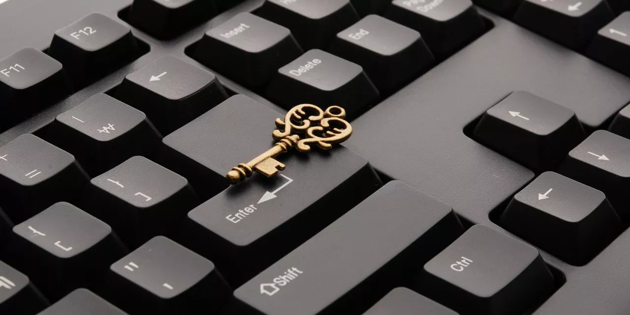 Ausschnitt einer schwarzen Tastatur. Darauf liegend ein goldener Schlüssel.