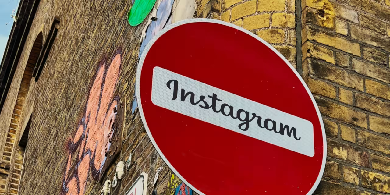 Detailaufnahme des Straßenschildes „Keine Durchfahrt“ (roter Kreis mit weißem Querbalken). Im weißen Bereich steht: „Instagram“. Im Hintergrund eine Klinkerwand mit Graffiti.