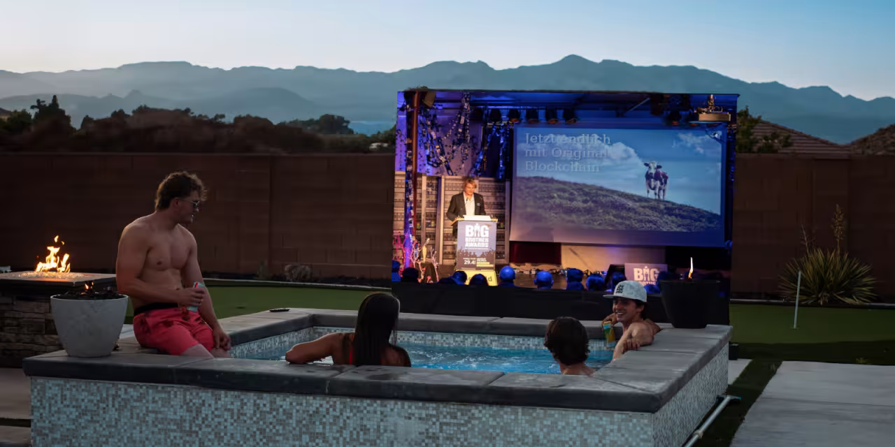 Fotomontage: Menschen in einem Whirlpool bei Dämmerung. Sie schauen auf eine Leinwand. Abgebildet ist ein Ausschnitt der BigBrotherAwards-Gala.