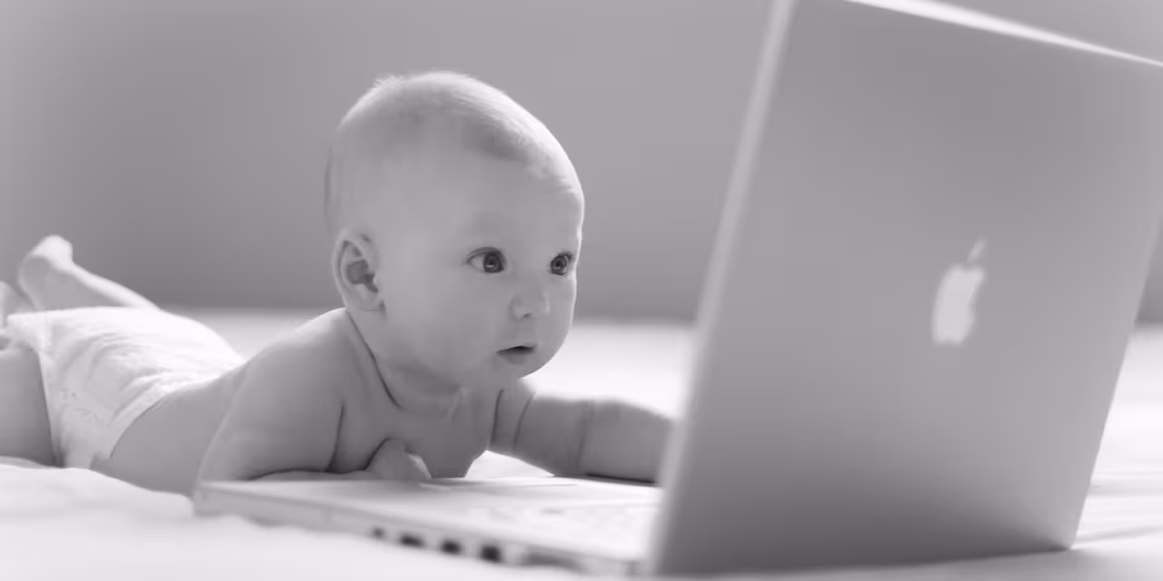 Ein Baby, das auf einen Laptop-Bildschirm starrt (schwarz-weiß).