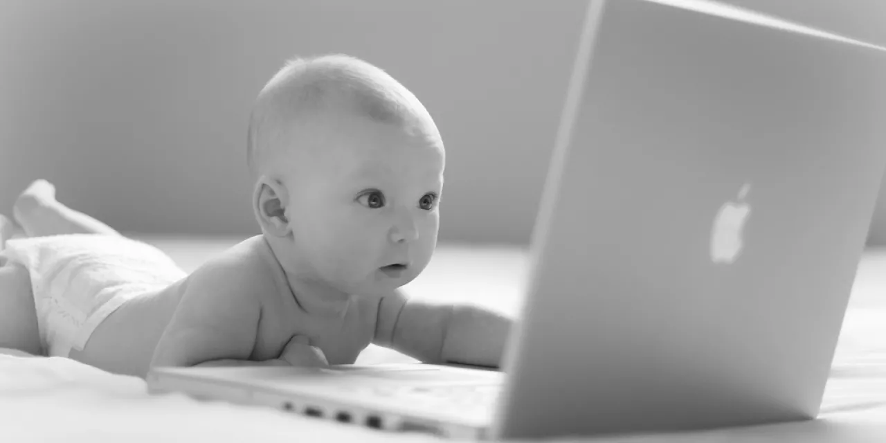 Ein Baby, das auf einen Laptop-Bildschirm starrt (schwarz-weiß).