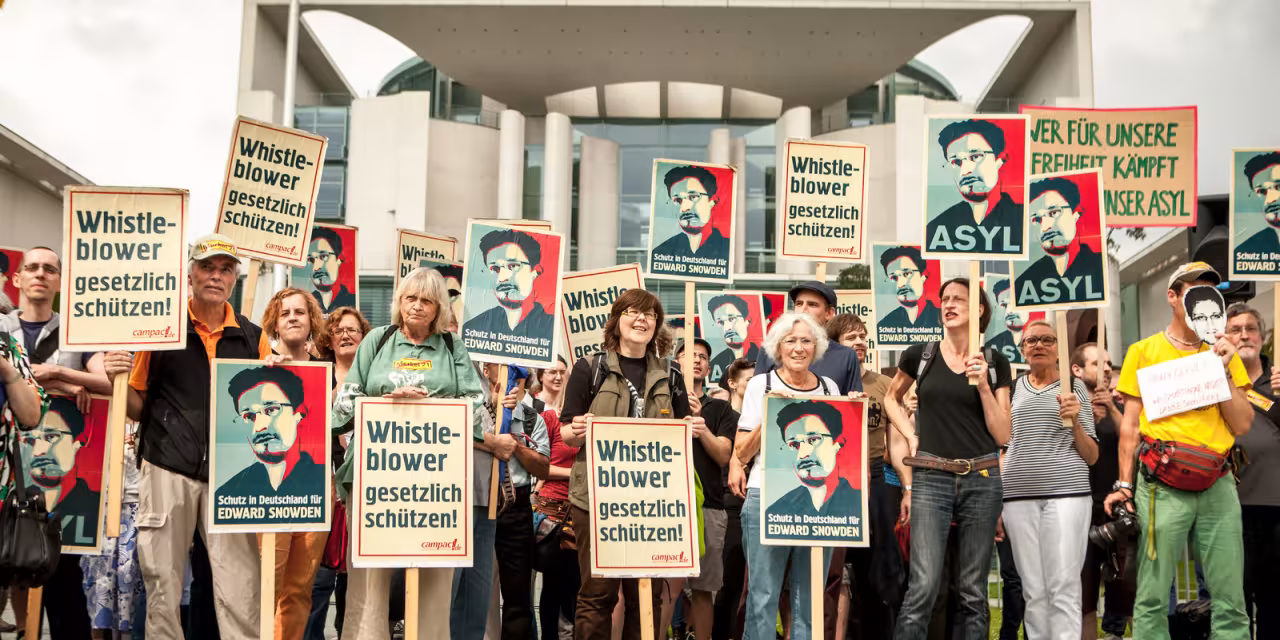 Aktivist.innen vor dem Bundeskanzler.innenamt mit Snowden-Demoschildern.