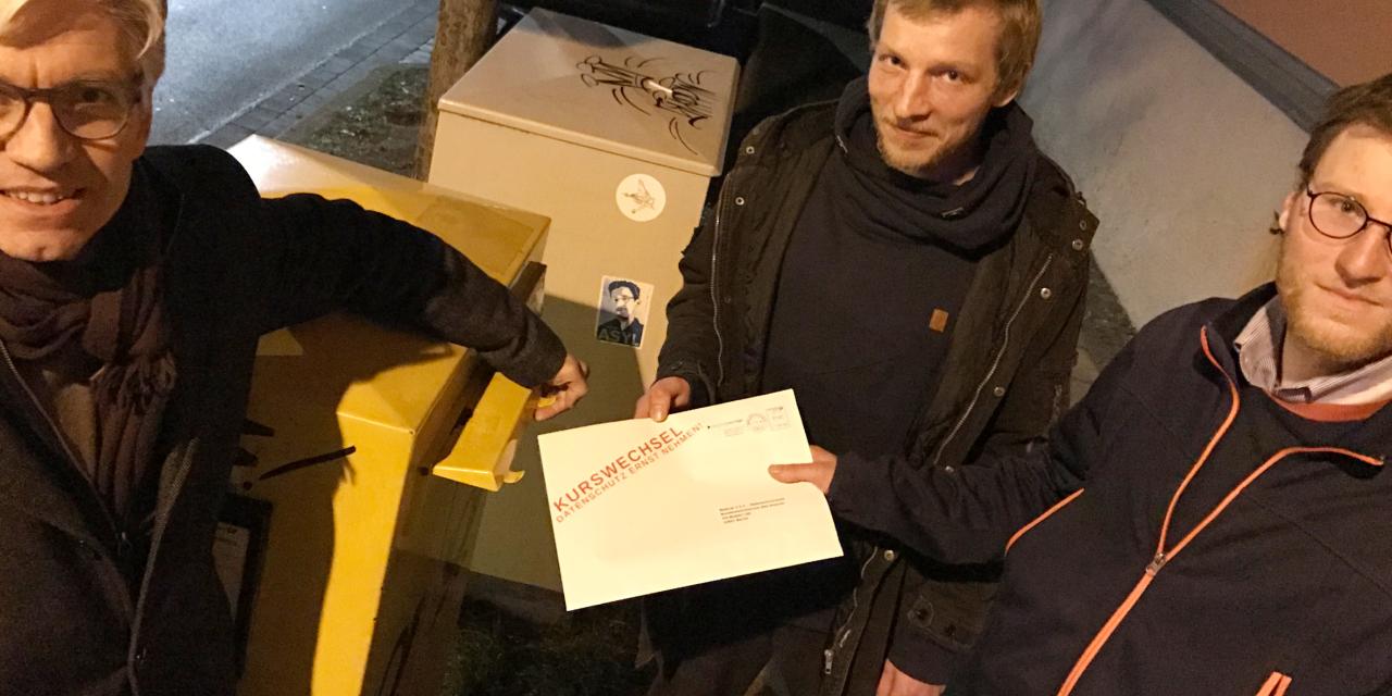 Mehrere Personen schmeißen einen Brief in einen Briefkasten.