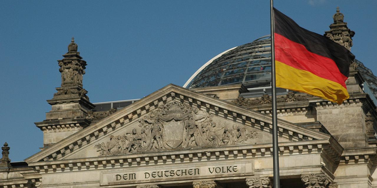 Oberer Gebäudeteil des Deutschen Bundestags (mit Kuppel und Deutschlandfahne).