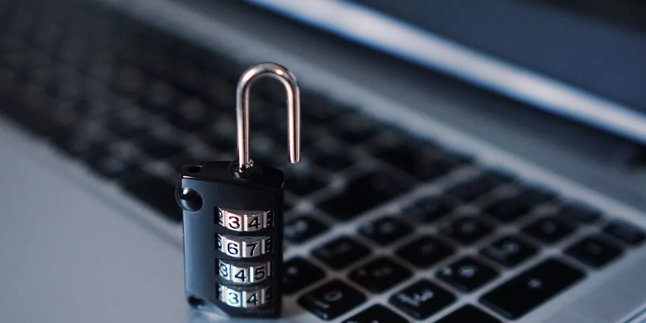 Ein Vorhängeschloss auf einer Laptoptastatur (Detailaufnahme).