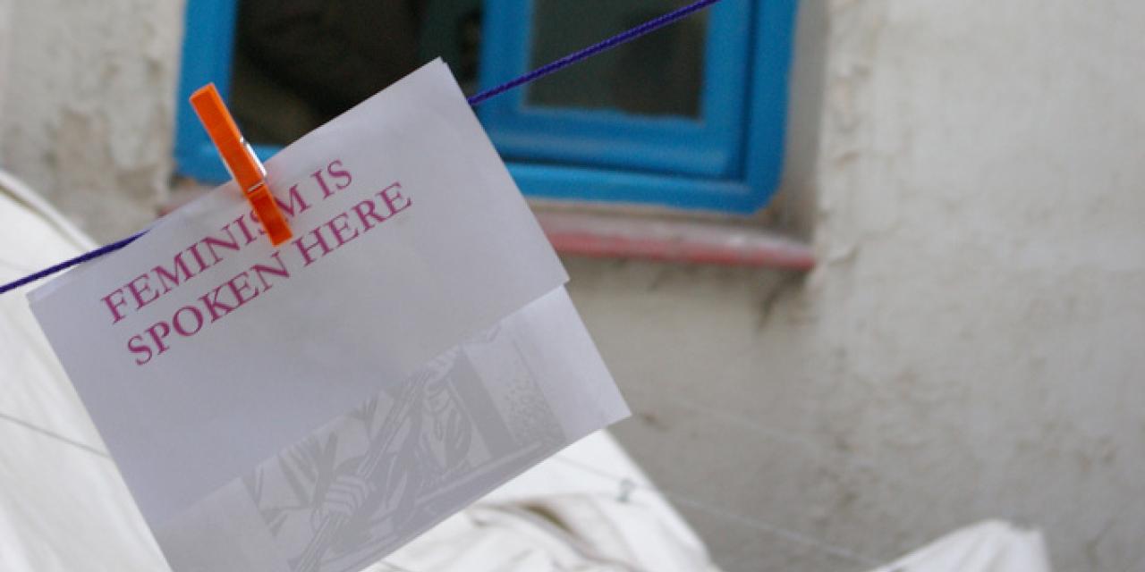 Ein Notizzettel an einer Wäschleine. Daruf steht: "Feminism is spoken here".