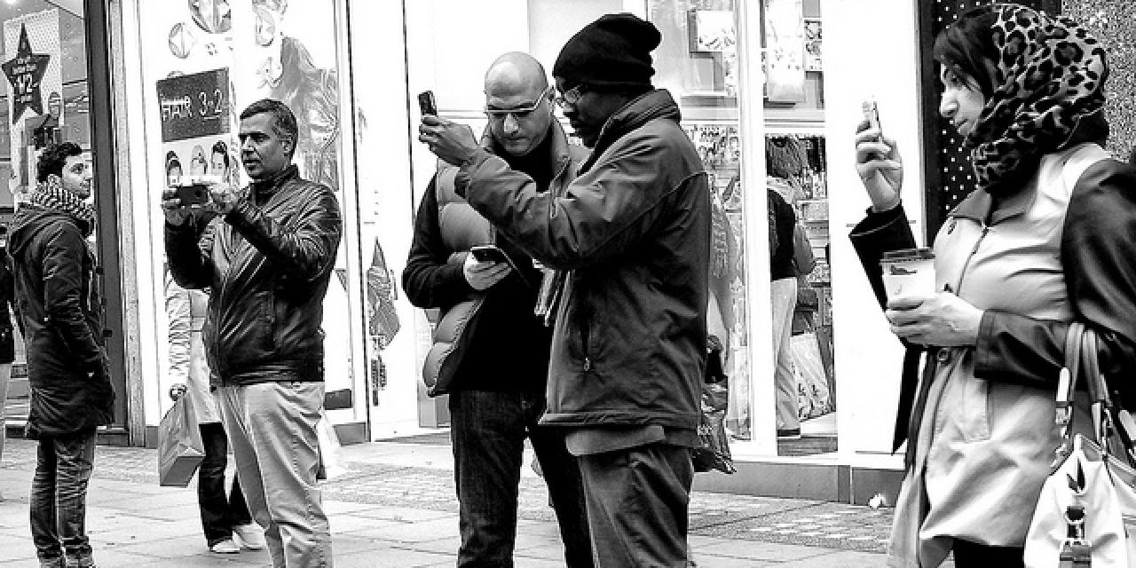Menschen, die in einer Einkaufsstraße stehen und auf ihr Handy schauen (schwarz-weiß).