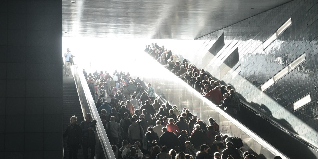 Viele Menschen auf einer breiten Treppe und Rolltreppe.