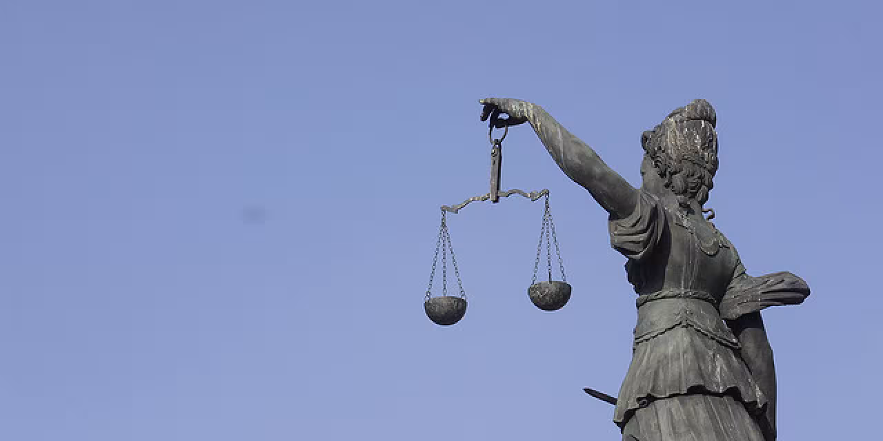 Eine Statue der Justitia mit einer Waagschale in der Hand.