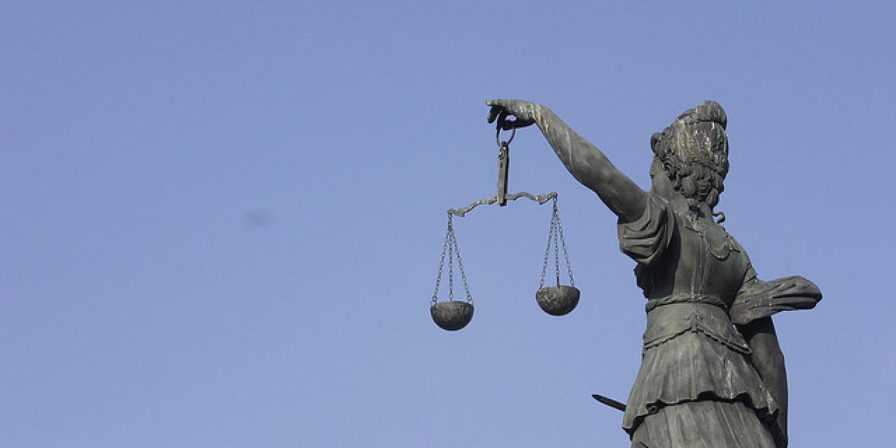 Eine Statue der Justitia mit einer Waagschale in der Hand.