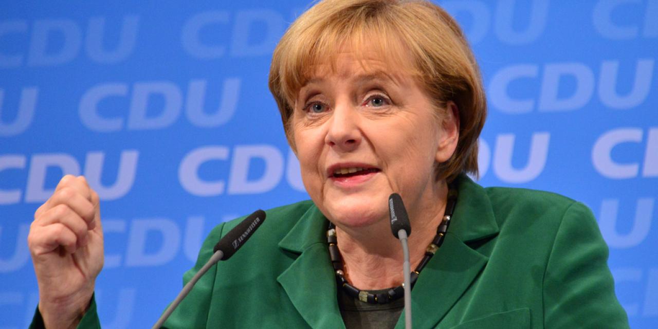 Portraitaufnahme von Angela Merkel, die an einem Mikrofon spricht.
