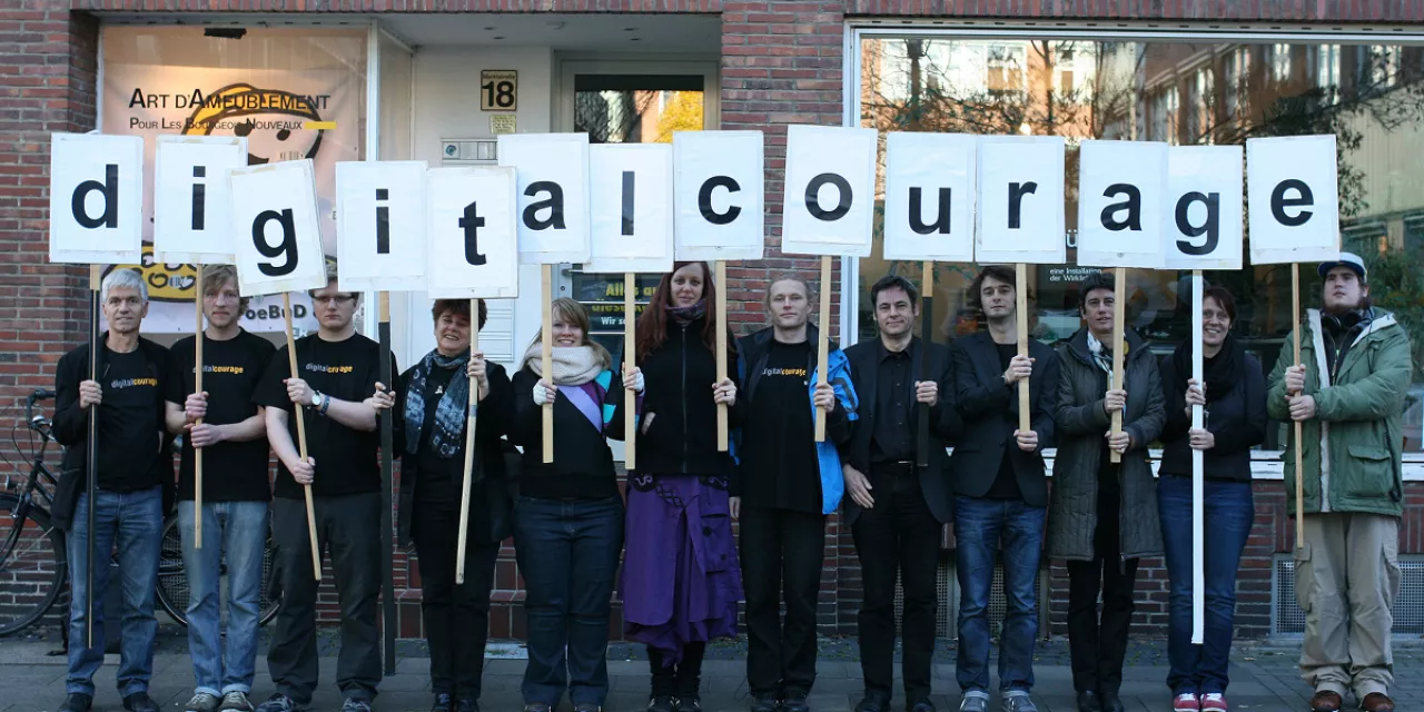 Das Team von Digitalcourage mit Schildern in der Hand, die das Wort Digitalcourage abbilden.