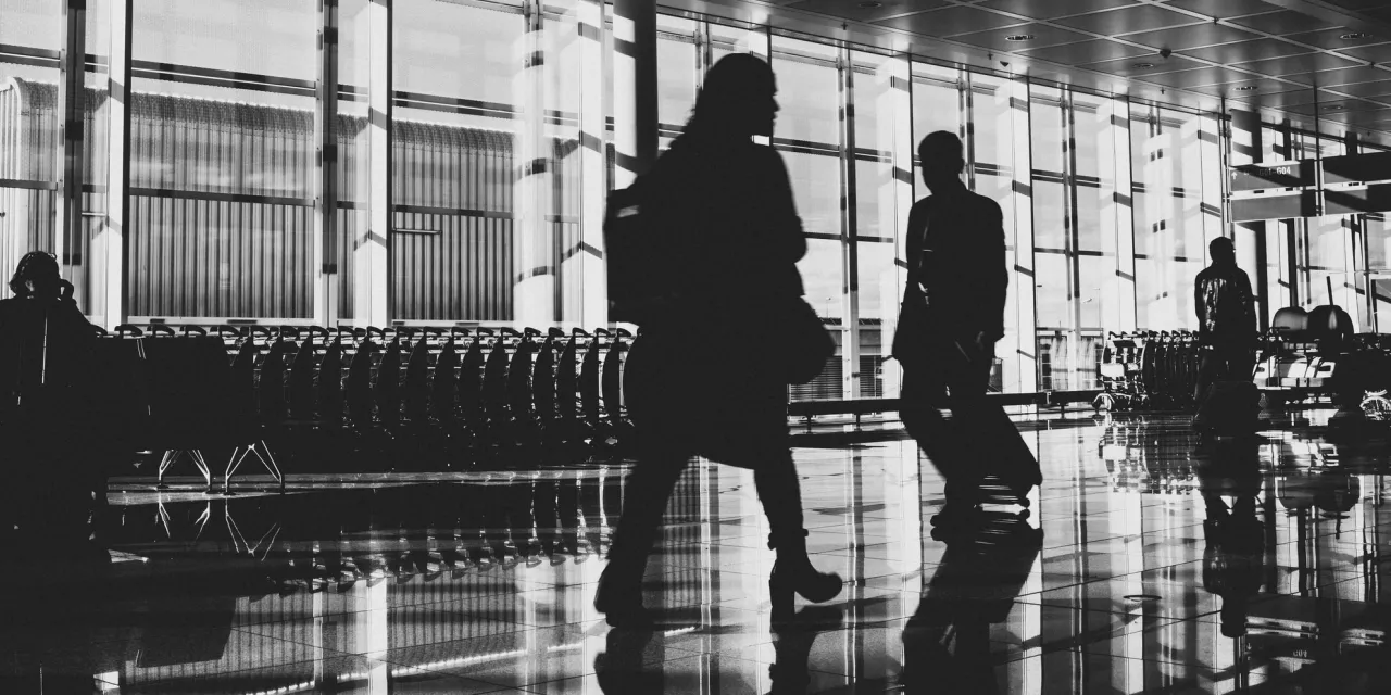 Ein schwarz-weiß Foto von Passagieren in einem Flughafenterminal.