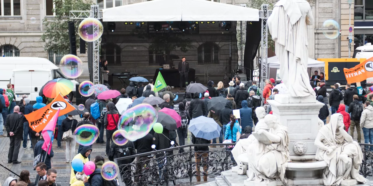 Viele Personen vor einer großen Bühne. padeluun hält eine Rede.