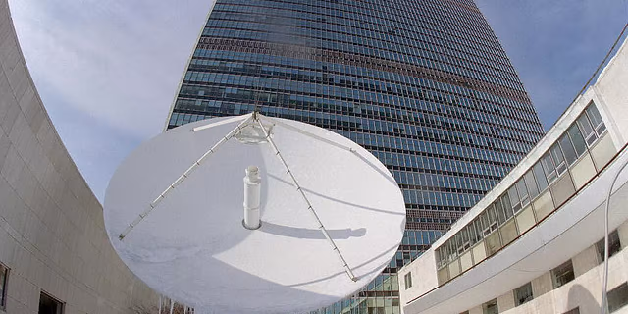 Eine riesige Satellitenschüssel vor einem Hochhaus.