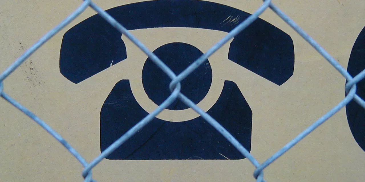 Symbol eines Telefons hinter Maschendrahtzaun.