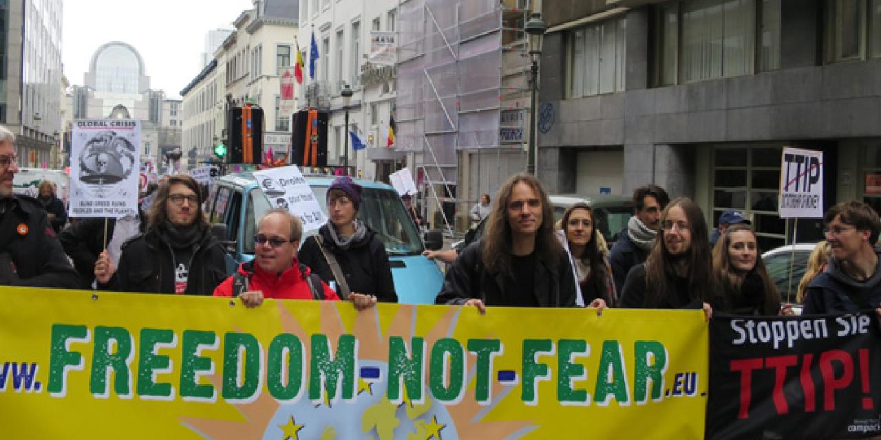 Demonstrant.innen mit einem Banner von "Freedom not Fear".