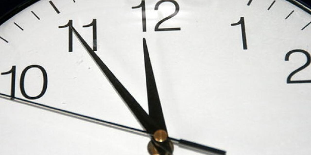 Eine Detailaufnahme einer Uhr mit dem großen Zeiger auf der elf und dem kleinen auf der zwölf.